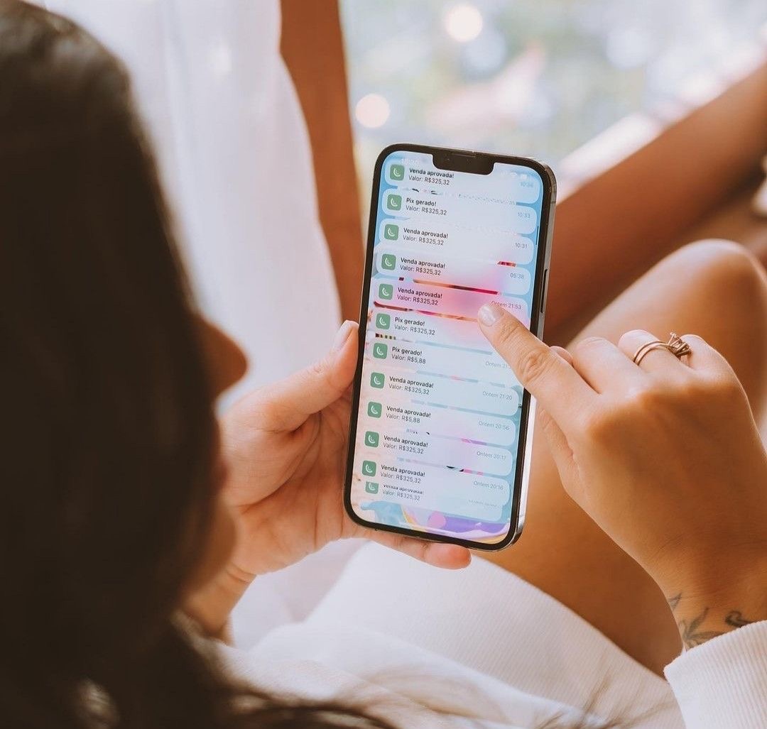 Creator segurando o celular com notificações de vendas